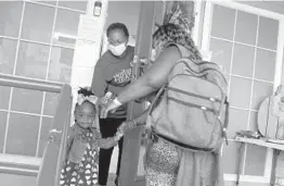  ?? MARTHA IRVINE/AP 2021 ?? Wanda Vincent prepares to check the temperatur­e of 2-year-old Olivia Grace Charles, who holds her mother’s hand at a day care center in Arlington, Texas.