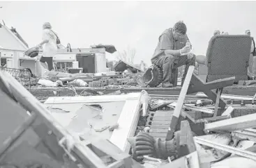  ?? Branden Camp / Associated Press ?? Jeff Bullard sits in what used to be his home as his daughter, Jenny, looks through the rubble in Adel, Ga. Jenny, 19, was knocked down by a collapsing wall of their home before finding her father trapped under debris.