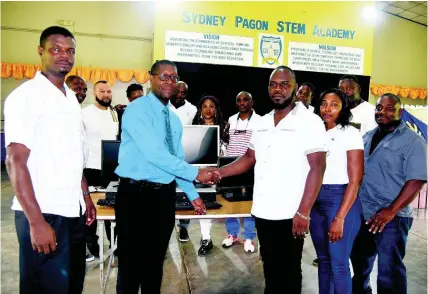  ?? PHOTO BY ANTHONY FOSTER ?? Dr Stenneth Davis (right) hands over a monitor to Sydney Pagon Academy Principal George Miller, while other members of the class of 1997 look on.
