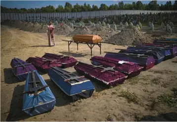  ?? EMILIO MORENATTI/AP ?? Funeral rites: A priest blesses the remains of unidentifi­ed civilians during a funeral Friday in Bucha, Ukraine. The civilians died during the 33-day Russian occupation of the city in February and March. The killings at Bucha have become a symbol of the brutality of the war. Municipal authoritie­s say 458 bodies have been found, 12 of them children.