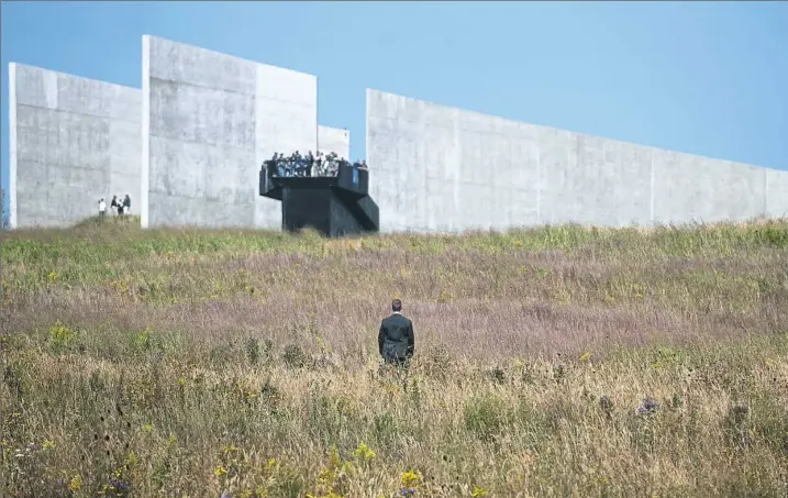  ?? Stephanie Strasburg/Post-Gazette ?? A lone security agent stands in a field of wildflower­s as people crowd onto the observatio­n deck at the Flight 93 National Memorial visitors center on Monday in Stonycreek. Families of the deceased joined Gov. Tom Wolf and Vice President Mike Pence for...