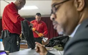 ?? Alexandra Wimley/Post-Gazette ?? Pittsburgh police firearms instructor­s Officer Jim Sippey and Officer Ken Sowinksi prepare a surrendere­d gun for storage on Monday as the Rev. Guy Brown, of the Church of the Holy Cross, adds a gun to the tally during a gun buyback day at the church in Homewood.
