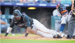  ?? DAVID ZALUBOWSKI/ASSOCIATED PRESS ?? Colorado’s Ian Desmond, left, slides safely into home plate after a single by teammate Tony Wolters in the fifth inning of the Rockies’ 9-8 loss to Houston.