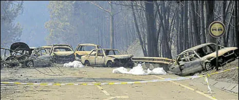  ?? AP ?? Burnt cars block a road in central Portugal on Sunday. Many people were killed when they were trapped in their vehicles during the fire.