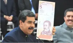  ??  ?? Venezuela’s President Nicolas Maduro holds a specimen of the new five-bolivar banknote during a meeting with ministers responsibl­e for the economic sector at Miraflores Palace in Caracas, Venezuela March 22. — Reuters photo