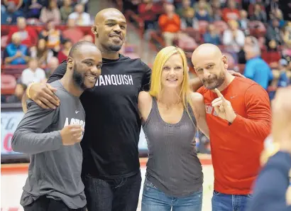  ?? ADOLPHE PIERRE-LOUIS/JOURNAL ?? From left, MMA fighters Chris Brown, Jon Jones and Holly Holm pose with coach Greg Jackson during the Lobos basketball game against San Jose State Wednesday.