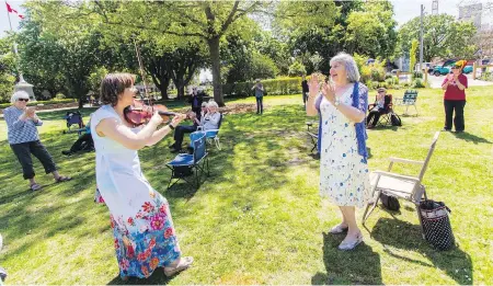  ?? DARREN STONE, TIMES COLONIST ?? Violinist Tatiana Kostour plays at a social-distancing concert for Helen Heenan, who celebrates her 75th birthday in Esquimalt’s Memorial Park.