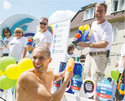  ?? JAMES PARK ?? Mayor Jim Watson, right, engages in a water fight with another participan­t during the Capital Pride Parade on Bank Street in 2014.