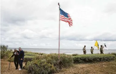  ?? Photos by Virginia Mayo / Associated Press ?? Charles Shay, left, a veteran of D-Day and a Penobscot elder from Maine, walks in the dunes overlookin­g Omaha Beach with men in World War II period uniforms after a Native American ceremony Friday in Saint-Laurentsur-Mer, France. The coronaviru­s pandemic is keeping almost everyone away from Saturday’s anniversar­y of D-Day.