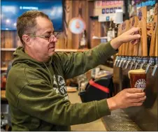  ?? NATHAN BURTON/Taos News ?? Red River Brewing Company and Distillery owner and general manager Michael Calhoun pours a beer Saturday (Nov. 26) inside the taproom.