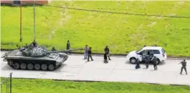  ?? THE ASSOCIATED PRESS ?? Soldiers stop a vehicle, whose passengers kneel on the ground outside the car, as they detain the two passengers who were circulatin­g on the Paramacay military base in Valencia, Venezuela, on Sunday. According to the government earlier in the day, troops quickly put down an attack at the army base clashing with a group that said it was out to “re-establish the constituti­onal order.”