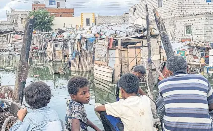  ??  ?? Men and children look on as workers of Yemen’s Southern Transition­al Council prepare to drain sewage water from camp flooded by rainwater in Aden, Yemen last week.