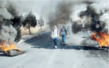  ??  ?? Activistas israelíes caminan entre gomas en llamas durante choques con policías.