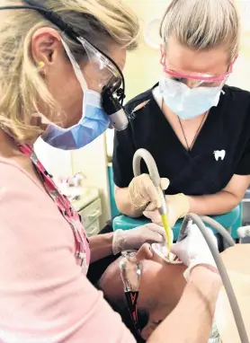  ?? PHOTO: PETER MCINTOSH ?? Getting their teeth into it . . . Dentistry on Musselburg­h dentist Saleema Reeves (left) and dental assistant Grace Meyer treat patient Jasmine Wright.