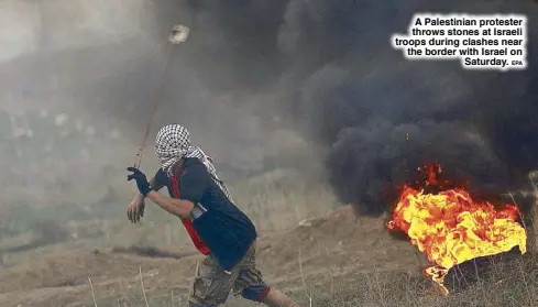  ??  ?? A Palestinia­n protester throws stones at Israeli troops during clashes near the border with Israel on Saturday.