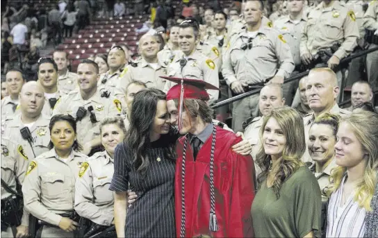  ?? Richard Brian Las Vegas Review-Journal @vegasphoto­graph ?? Arbor View High School senior Daxton Alyn Beck gets a hug from his mother, Nicole Beck, as they gather for a photo with a group of Metro officers at his graduation ceremony Saturday at the Thomas & Mack Center.