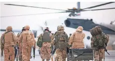  ?? FOTO: DPA ?? Bundeswehr­soldaten tragen auf dem Flughafen im afghanisch­en Masar-i-Scharif eine Feldkiste zu einem Hubschraub­er.