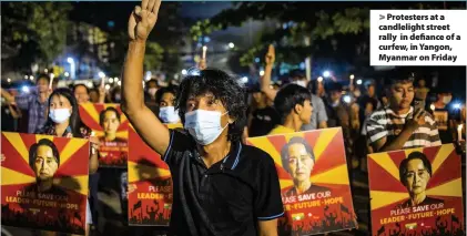  ??  ?? > Protesters at a candleligh­t street rally in defiance of a curfew, in Yangon, Myanmar on Friday