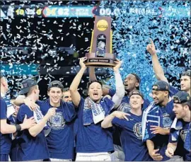  ?? David J. Phillip Associated Press ?? VILLANOVA PLAYERS CELEBRATE with the trophy after dominating Michigan in the championsh­ip game of the Final Four.