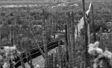  ?? AP PHOTO/MATT YORK ?? This Feb. 17, 2006, file photo shows a fence separating Organ Pipe Cactus National Monument (right) and Sonyota, Mexico, running through Lukeville, Arizona.