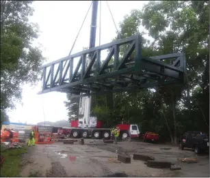  ?? Call photo/Joseph Fitzgerald ?? RIDOT contractor­s installed a 182-foot truss style bridge over the Blackstone River between Woonsocket and North Smithfield on Monday afternoon. Here, a crane lifts one of the bridge sections as the day’s work commences.
