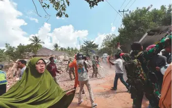  ?? AFP ?? People react shortly after an aftershock hits the area in Tanjung on Lombok island yesterday. Videos showed rubble strewn across streets and clouds of dust enveloping buildings.