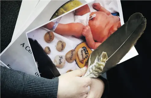  ?? JOHN WOODS / THE CANADIAN PRESS ?? A woman holds a photo of a baby and an eagle feather at a press conference in support of the mother whose newborn baby was seized from hospital by Manitoba’s Child and Family Services (CFS) in Winnipeg on Friday.