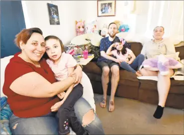  ?? Peter Hvizdak / Hearst Connecticu­t Media ?? Melissa Ortiz, left, holding her daughter Julia Ortiz, 10, who has Rett syndrome and is paralyzed, with her husband Anthony Ortiz, on the couch with their daughters Isabelle Ortiz, 6, and Aariana Richards, 17, are trying to raise money for a wheelchair van for Julia.