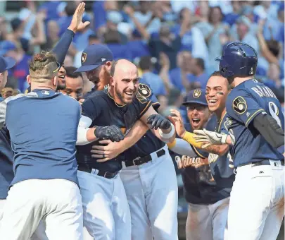  ?? BENNY SIEU / USA TODAY SPORTS ?? Travis Shaw of the Brewers is mobbed by teammates after his game-winning two-run home run off Cubs reliever Wade Davis in the 10th inning on Saturday afternoon at Miller Park.