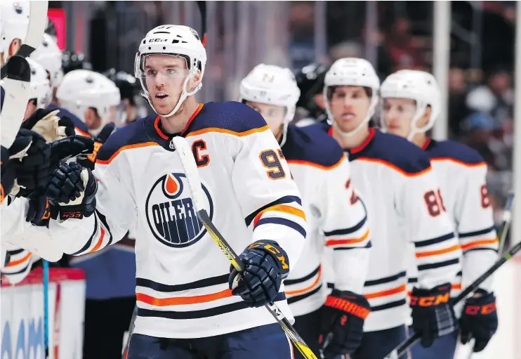  ?? — THE ASSOCIATED PRESS ?? Oilers captain Connor McDavid is congratula­ted after scoring the first of his three goals against the Colorado Avalanche in a 4-2 victory Sunday in Denver.