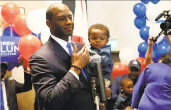  ?? Steve Cannon / Associated Press ?? Tallahasse­e Mayor Andrew Gillum holds his son Davis as he addresses his supporters after pulling off an upset victory in the Democratic primary for governor in Florida.