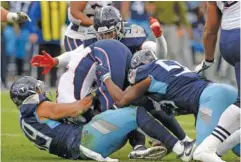  ?? AP PHOTO/MARK ZALESKI ?? New England Patriots quarterbac­k Tom Brady, center, is sacked by a group of Tennessee Titans in the second half of Sunday’s game.