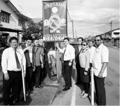  ??  ?? Dr Teh (fifth right) hangs a poster in a residentia­l area.