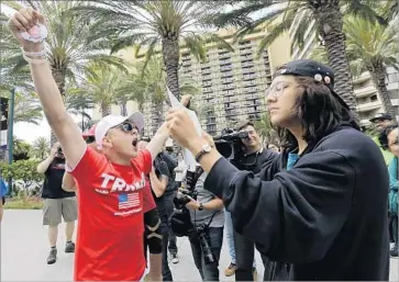  ?? Irfan Khan Los Angeles Times ?? A TRUMP SUPPORTER, left, faces off with a protester outside the Republican’s campaign rally last month in Anaheim. One GOP consultant said Trump’s candidacy “could potentiall­y backfire for years to come.”