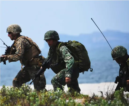  ?? TED ALJIBE/AGENCE FRANCE-PRESSE ?? PHILIPPINE and US Marines take position as they simulate an amphibious landing as part of the annual joint military exercise at the beach of Philippine navy’s training camp in San Antonio, Zambales on May 9, 2018.