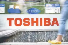  ??  ?? Pedestrian­s walk past a logo of Toshiba Corp outside an electronic­s retailer in Tokyo. Shares in Toshiba dived more than 12 per cent on reports it is likely to record a huge special loss related to a US subsidiary’s acquisitio­n of a nuclear power...