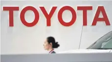  ?? FOTO: AFP ?? Toyota-Mitarbeite­rin vor dem Schriftzug ihres Arbeitgebe­rs: Der Fokus auf die Hybridtech­nik zahlt sich für den japanische­n Autobauer aus.