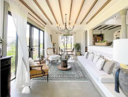  ?? ?? Beams from salvaged woods add visual depth to the living room. A built-in concrete bench, which also functions as a storage space, blends with the French chairs.