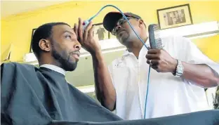  ?? KAYLA O’BRIEN/STAFF ?? John Henry, owner of J. Henry’s Barber Shop across from the new Orlando City Stadium in Parramore, trims a customer’s hair last week. He’s hoping to find more clients among the game-day crowds.