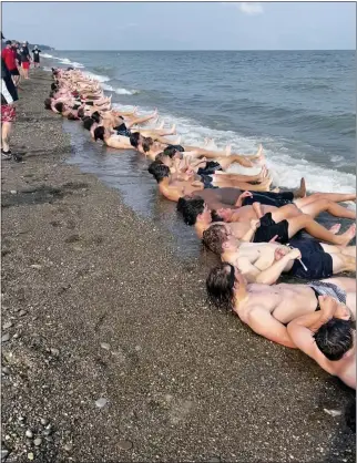  ?? COURTESY MITCH HEWITT ?? Members of the Chardon football team do leg-lifts in the sand at Mentor Headlands beach on Aug. 1, the first day of football practice in Ohio