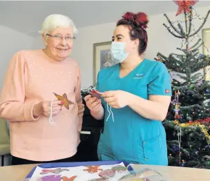  ??  ?? Carer Stacie Burrows helping resident Jean decorate the tree