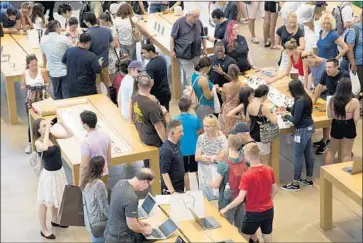  ?? Mark Lennihan Associated Press ?? CUSTOMERS BROWSE in an Apple store in New York. The consumer technology giant’s market value stood at $1.002 trillion on Thursday. Amazon.com, Alphabet and Microsoft are worth more than $800 billion each.