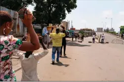  ?? PIERRE FAVENNEC/AFP VIA GETTY IMAGES ?? People walk with their hands up as they pass security checkpoint­s, held by security forces wearing civil clothes and holding machetes and sticks to control the crowd, in Lagos, Nigeria on Friday.