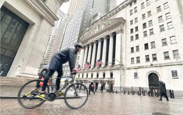  ?? File/ Associated Press ?? ↑
A bicyclist passes the New York Stock Exchange.