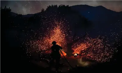  ?? Photograph: Frederic J Brown/AFP/Getty Images ?? A firefighte­r sprays a tree as the Bobcat fire burns in Juniper Hills, California, on 19 September.