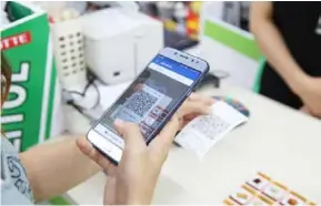  ?? VNA/VNS Photo ?? A customer pays for goods by scanning a QR code. The widespread use of mobile money will create an important boost to the growth of e-payments in Việt Nam and promote the country's digital transforma­tion.