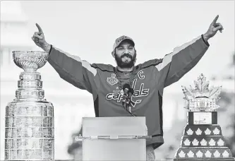  ?? RICKY CARIOTI THE WASHINGTON POST ?? The Capitals Alex Ovechkin, flanked by the Stanley Cup, left, and his Conn Smythe Trophy, addresses fans during the victory parade and rally in Washington, D.C.