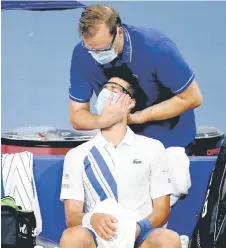  ?? Photo — AFP ?? Djokovic receives treatment between games while playing Ricardas Berankis of Lithuania during the Western & Southern Open at the USTA Billie Jean King National Tennis Center in the Queens borough of New York City.