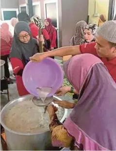  ??  ?? SEBAHAGIAN kakitangan MIDA bergotong-royong bersama penduduk menyediaka­n bubur lambuk.