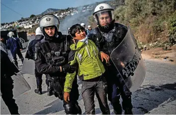  ?? AFP ?? Polizisten führen auf Lesbos einen jungen Asylbewerb­er vom Flüchtling­slager Moria auf Lesbos ab.